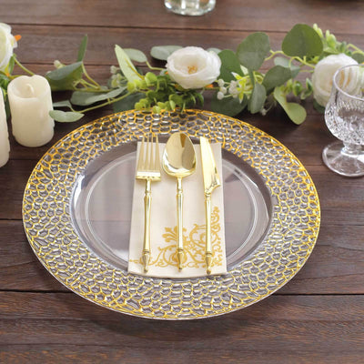 Elegant gold-accented dinner plate set with cutlery and napkin on a wooden table.