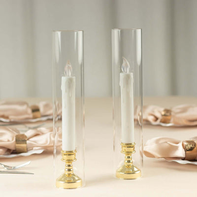 Elegant candle holders with white candles and gold bases on a soft table setting.