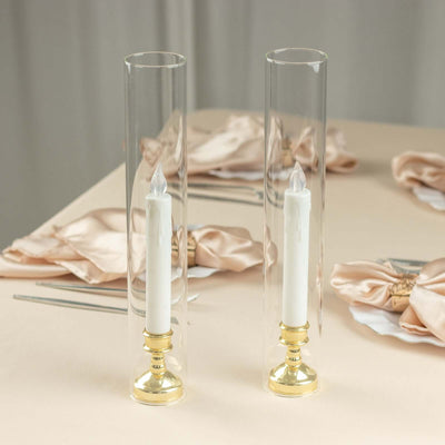 Elegant glass candle holders with white candles and gold bases.