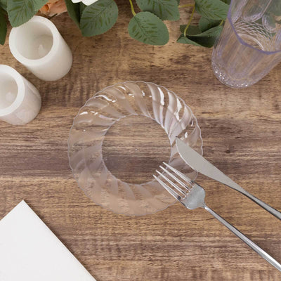 Clear decorative plate with silver fork and knife on wooden table.