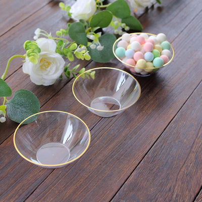 Elegant clear glass bowls with gold rim, arranged with pastel decorative balls.