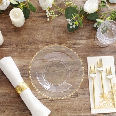 Elegant clear plate with gold beaded rim on rustic wooden table setting.