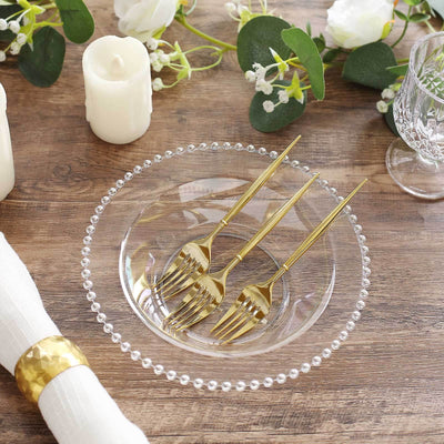 Elegant glass bowl with gold forks and decorative elements on a wooden table.