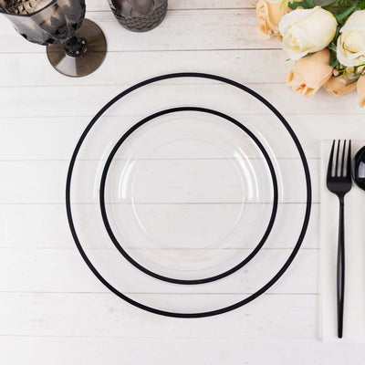 Clear plates with black rims on a white wooden table, surrounded by floral decor.