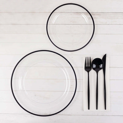 Clear plates with black rims and black cutlery on a white background.