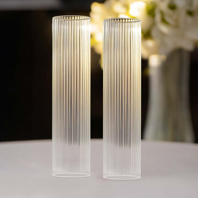 Clear ribbed glass vases set against a blurred floral background.