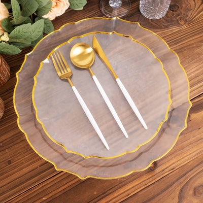 Elegant clear charger plates with gold trim and white utensils on a wooden table.