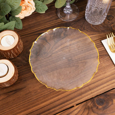 Elegant clear plate with gold trim on rustic wooden table.