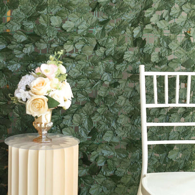 Floral arrangement in a glass vase on a pedestal table with a white chair.