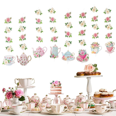 Tea party decor featuring floral teapots, cups, and sweets on a table.