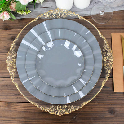 Gray decorative plates with ornate gold trim stacked on a wooden table.