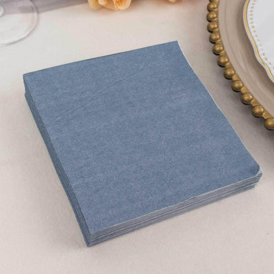 Blue paper napkins stacked on a neutral table setting.
