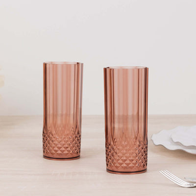 Set of two elegant rose-colored tall glasses on a wooden surface.