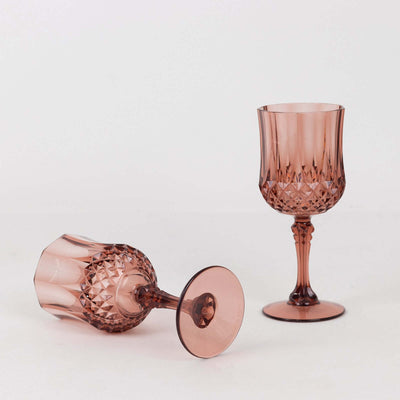 Pink crystal goblets in elegant designs, one upright and one tilted.