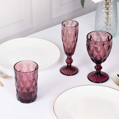 Set of three elegant purple glassware pieces on a table setting.
