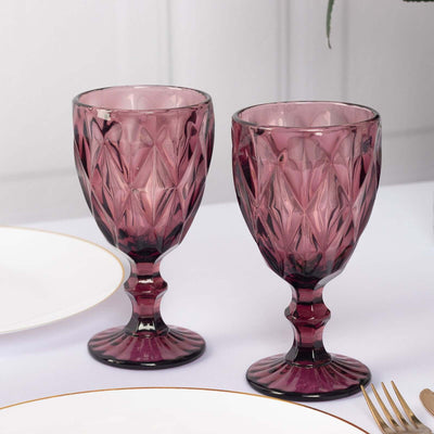 Set of two elegant purple glass goblets on a white table.