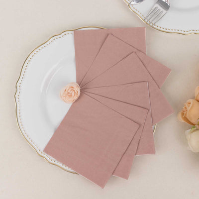 Set of blush pink napkins arranged on an elegant plate with a flower accent.