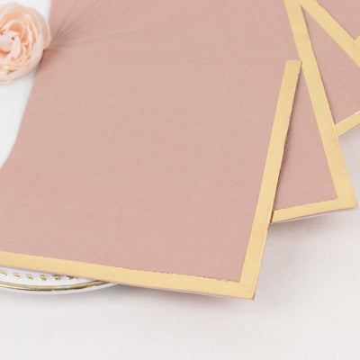 Rose gold envelopes with gold foil edges on a decorative plate.
