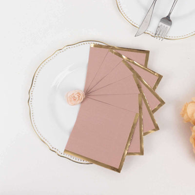 Blush pink envelopes with gold foil edges arranged on an elegant plate.