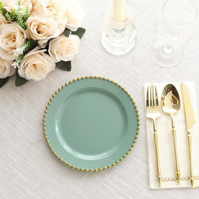 Mint green plate with gold beaded rim beside silver cutlery and white roses.
