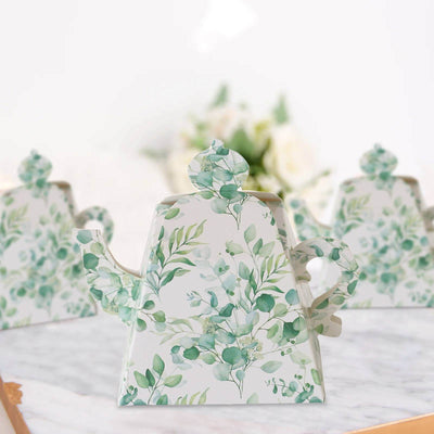 Decorative teapot with green leaf design on a white background.