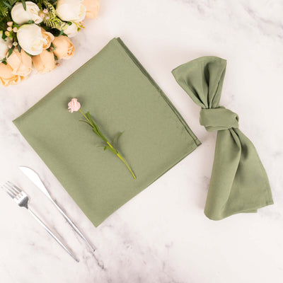 Olive green napkin and tied napkin with flower, styled with cutlery and flowers.