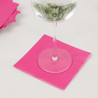 Pink paper napkin under a wine glass on a plain surface.