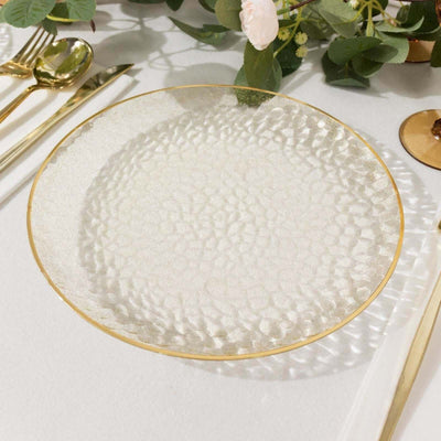 Textured glass plate with gold rim on a white table setting.