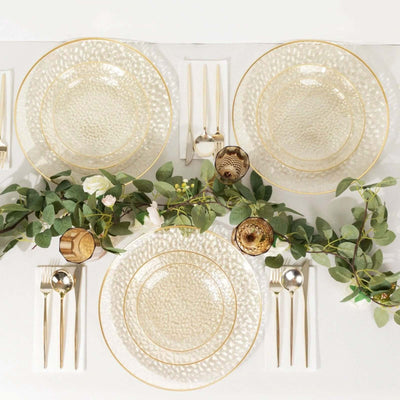 Elegant glass dinnerware set with gold accents and greenery decor.