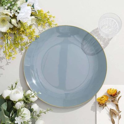 Gray dinner plate with gold rim surrounded by flowers and a glass.