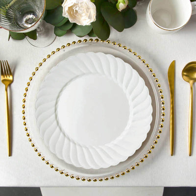 Elegant white plate with gold beaded rim, styled with golden cutlery and floral accents.
