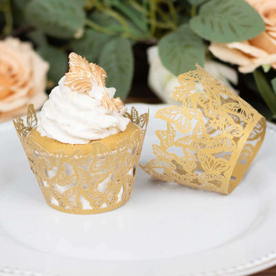 Gold butterfly cupcake wrappers on a plate with decorative flowers in the background.