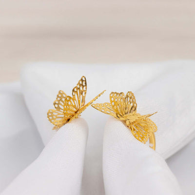 Gold butterfly earrings showcased on a white fabric background.