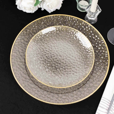 Elegant textured dinner plates with gold trim on a black table setting.