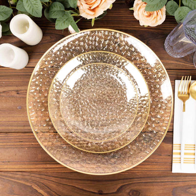 Elegant gold-rimmed glass plates stacked on a rustic wooden table.