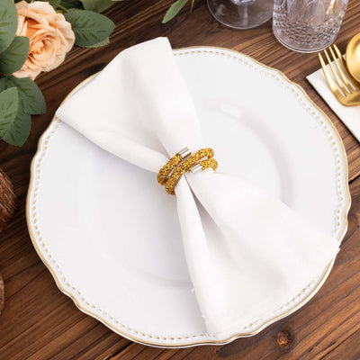 Elegant gold napkin rings on a white plate with a folded napkin.