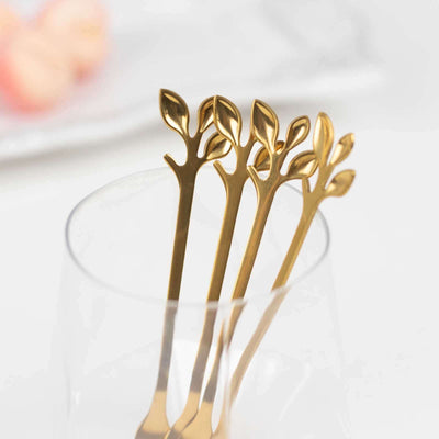Gold leaf design cocktail forks in a glass.