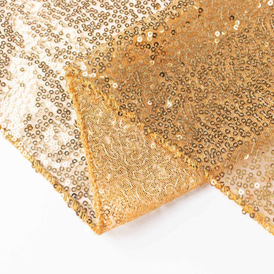 Gold sequin fabric draped elegantly on a plain background.
