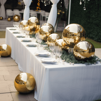 Gold decorative spheres on a festive table setting with glassware and greenery.
