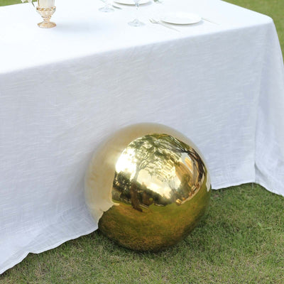 Shiny gold decorative orb under a white tablecloth on grass.