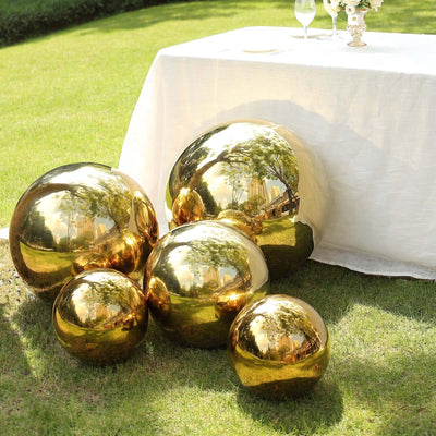 Golden decorative spheres arranged in a garden setting near a table.
