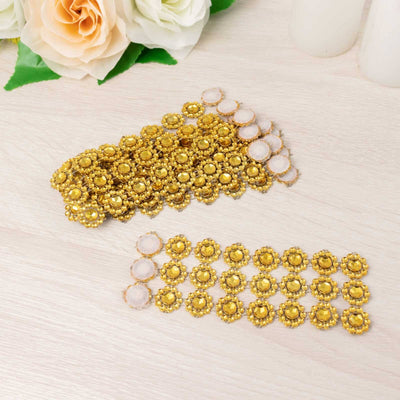 Gold decorative embellishments arranged in two rows on a light wooden surface.