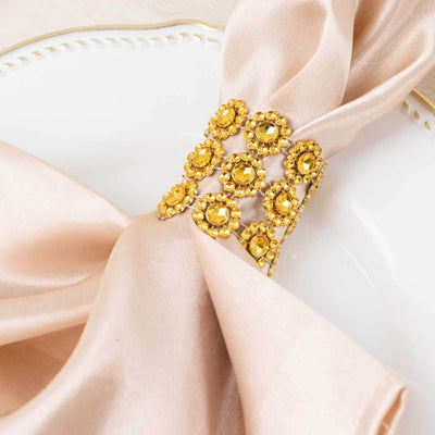 Silk napkin with a gold jeweled napkin ring on a decorative plate.