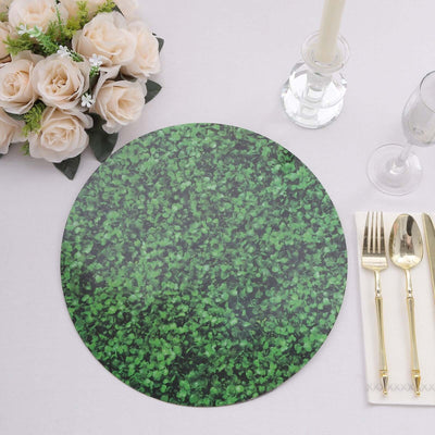 Green leafy placemat on a dining table with cutlery and flowers.