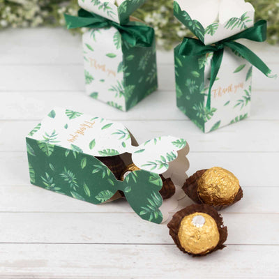 Green gift boxes with ribbons and golden candies on a wooden surface.