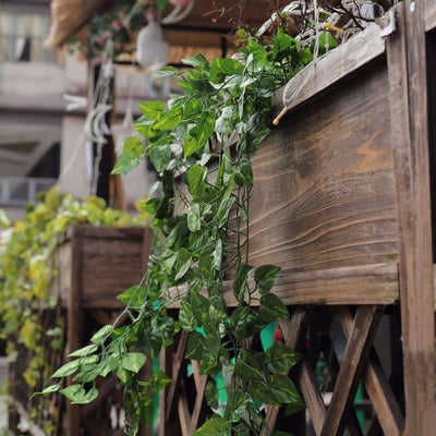 Artificial green vine hanging from a wooden planter.