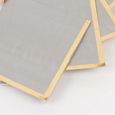 Gray and gold bordered paper sheets in a stack.