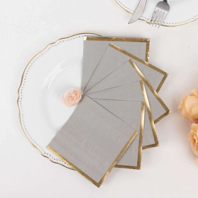 Elegant gray napkins with gold trim arranged on a decorative plate.