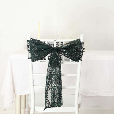 Green sequin chair sash bow on a white chair against a light background.