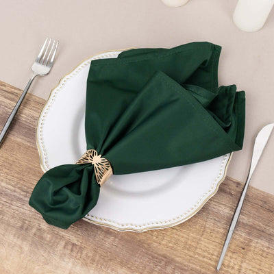 Green napkin elegantly tied on a decorative plate with cutlery.